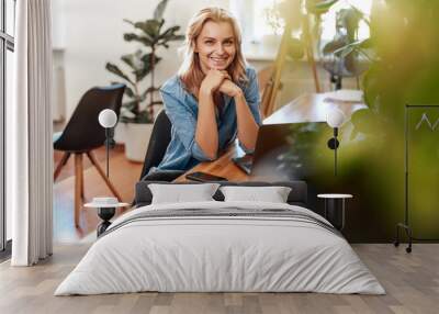 Joyful young woman poses in office room with laptop at table Wall mural