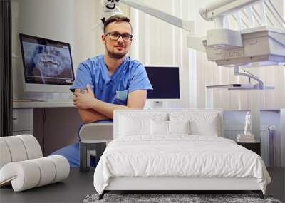 Male dentist in a room with medical equipment on background. Wall mural