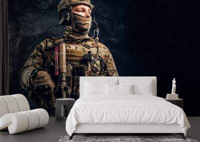 Modern special forces soldier in camouflage uniform looking sideways. Studio photo against a dark textured wall. Wall mural