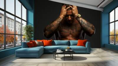 muscular man with tattooes in deep shadows Wall mural