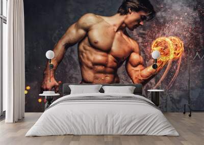 Portrait of a man with burning dumbbell. Wall mural