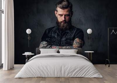 Portrait of a stylish bearded guy with tattooed hands. Studio photo against dark wall Wall mural