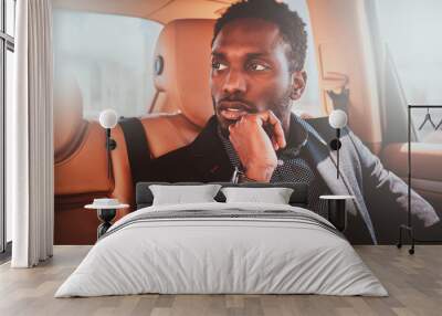 Portrait of pensive elegant afro etnicity businessman in the car as a passenger. Wall mural