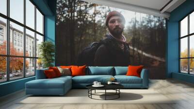 Portrait of young bearded hipster with backpack in the autumn forest. Wall mural