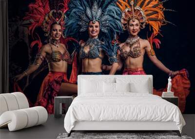 Three beautiful young womans in traditional brasilian carnaval costumes are posing for photographer at studio. Wall mural