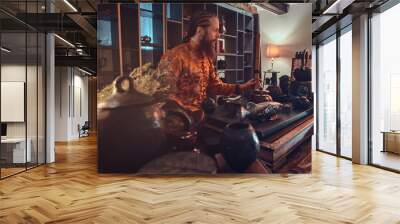 Tradition, health, harmony. Chinese tea ceremony. Caucasian master in kimono holding a bamboo flute while making natural tea in the dark room with a wooden interior Wall mural