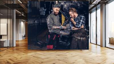 Two mechanics talking during repairs a broken car in a garage. Wall mural