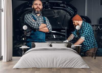 Two men repairing a car in a garage. Wall mural