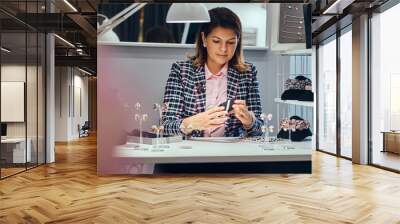 Woman seller packs precious earrings in a box for her client in a luxury jewelry store. Wall mural