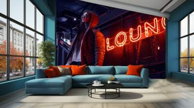 Young stylish girl wearing sunglasses with a coat covering his shoulders standing on stairs at underground nightclub with industrial interior Wall mural