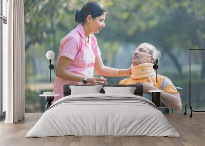 Nurse talking to male senior patient on wheelchair with a neck brace at the park. Wall mural