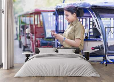 Woman driver sitting in e rickshaw and showing mobile phone screen Wall mural