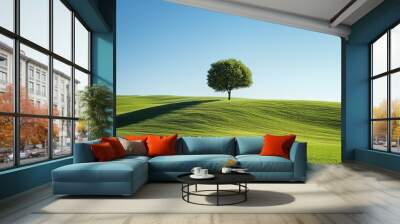 A single tree on the far horizon of rolling green hills, with a clear blue sky overhead Wall mural