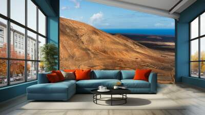 Timanfaya National Park in Lanzarote, Spain. Barren volcanic landscape with craters and a blue sea in the background. Wall mural