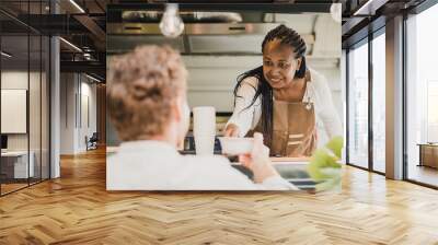 African chef woman serving take away order inside food truck - Focus on senior woman face Wall mural