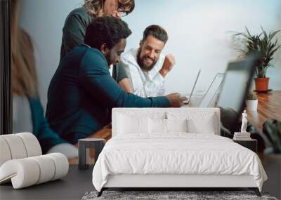 Content diverse coworkers examining papers near laptops Wall mural