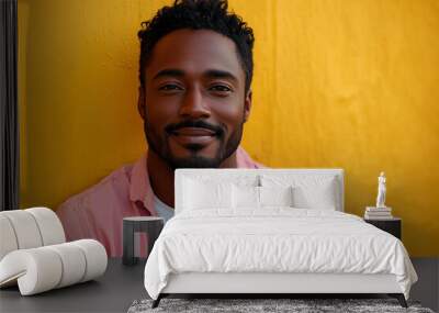 A happy black man wearing casual smiling at the camera, standing in front of an isolated yellow background. He is looking to his right and has short hair. The scene captures him from waist up, dressed Wall mural