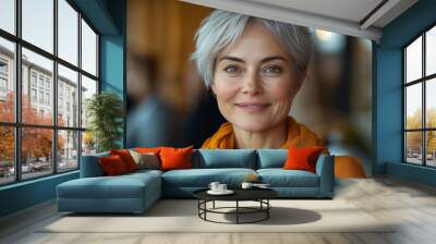 An attractive senior woman with short hair smiling at the camera in an environment of people Wall mural