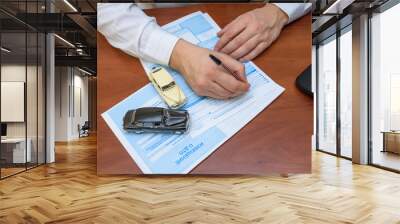 Hands filling a notice of an accident and two machines, standing on documents Wall mural