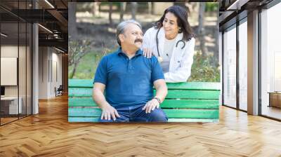 Portrait of happy mature female indian doctor wearing apron and senior male patient outdoor in the park, healthcare profession. Wall mural