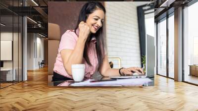 Young happy indian woman entrepreneur working on laptop computer in office. Wall mural