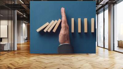 Business crisis manager stopping falling dominos from collapsing Wall mural