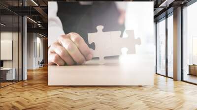 Businessman holding two joined matching puzzle pieces Wall mural