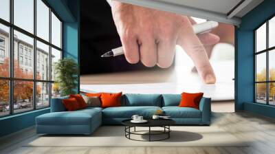 Businessman reading contract or document in folder pointing with his finger to an important part Wall mural