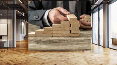 Front closeup view of businessman constructing steps of wooden p Wall mural