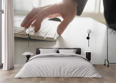 Male hand in a suit typing on white computer keyboard Wall mural