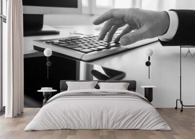 Monochrome image of businessman typing on a computer keyboard in office Wall mural