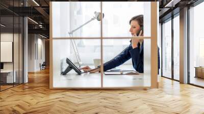 Young businesswoman or secretary dialing a phone number Wall mural