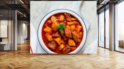 Potatoes stewed with meat, in tomato sauce, with spices and herbs, no people, on a white table, Wall mural