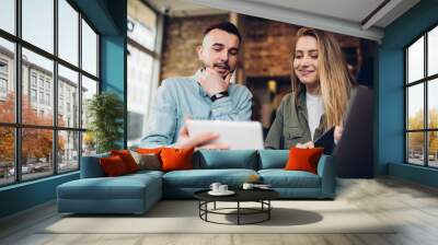 Cheerful couple watching tablet in cafe Wall mural