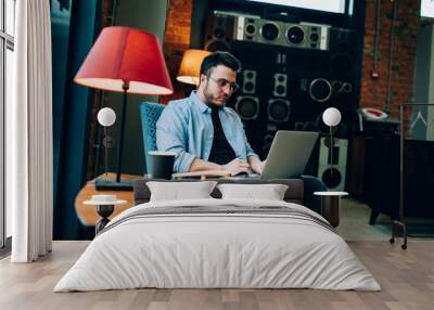 Young male entrepreneur in casual wear working with laptop at cafe Wall mural