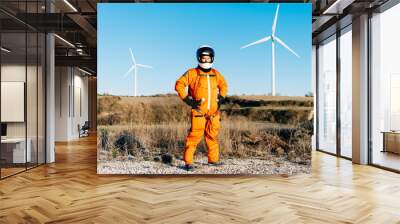 Mature man in a spacesuit standing against wind turbines Wall mural