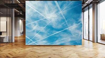 A blue sky with wispy clouds and contrails. Wall mural