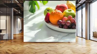 A bowl of fresh fruit on a table with a green plant in the background. Wall mural