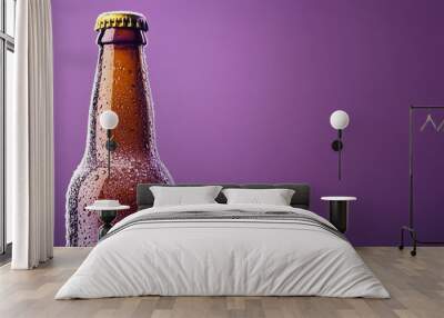 A cold beer bottle with condensation on it against a purple background. Wall mural