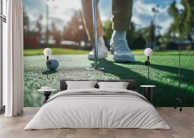 A golfer prepares to take a swing on a green golf course. Wall mural