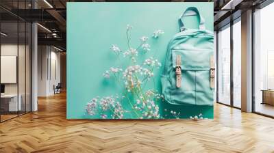 A light blue backpack with white flowers on a teal background. Wall mural