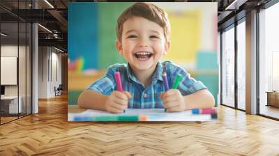 A little boy smiles happily while coloring with markers. Wall mural