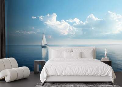 A sailboat on the calm ocean with a blue sky and white clouds. Wall mural