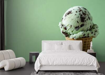 A scoop of mint chocolate chip ice cream in a waffle cone on a green background.  Sweet and refreshing. Wall mural