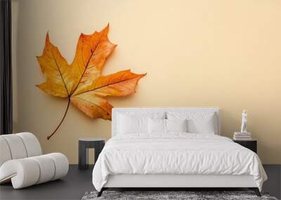 A single yellow maple leaf on a light beige background. Wall mural