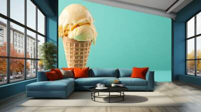 A waffle cone with two scoops of vanilla ice cream on a teal background. Wall mural