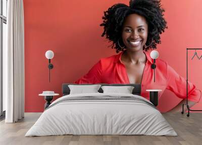 A woman with curly hair smiles brightly in a red shirt. Wall mural