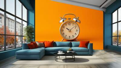 An alarm clock sitting on an orange background. Wall mural