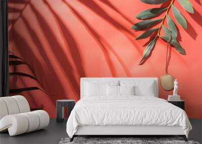 Tropical leaves with a gold necklace on a coral background. Wall mural