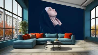 A nun on a blue background raised her face to the sky. Postcard with a picture of a young girl with an empty space for your description Wall mural